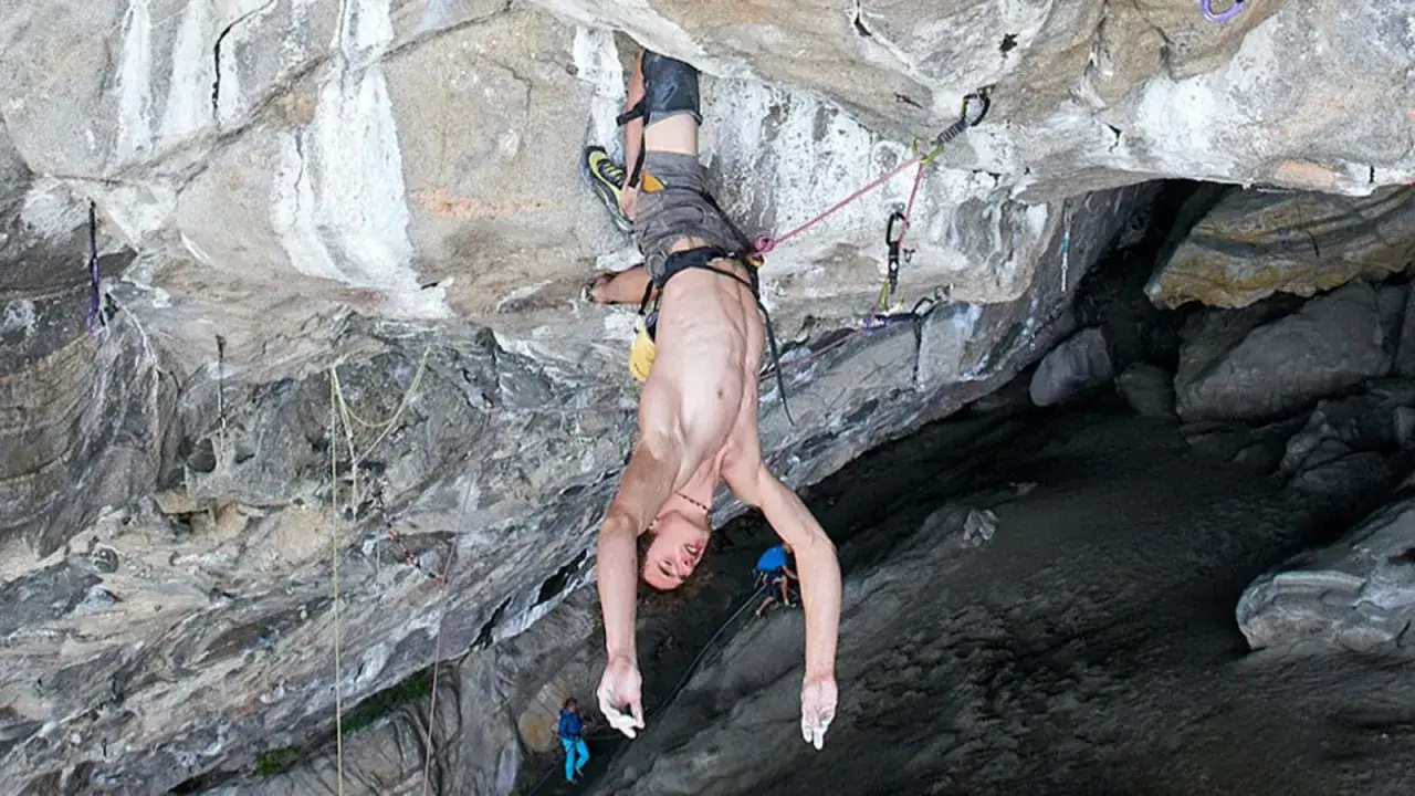 Adam Ondra h&auml;ngt kopf&uuml;ber an einer Felswand. Die Stille des Augenblicks wird nur vom leisen Rauschen der Seile unterbrochen.