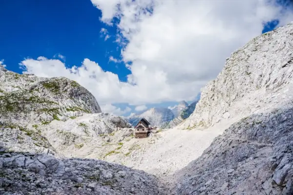 Hütte in den Julischen Alpen, idealer Rastplatz für eine Triglav Wanderung. Majestätische Berglandschaft unter blauem Himmel.