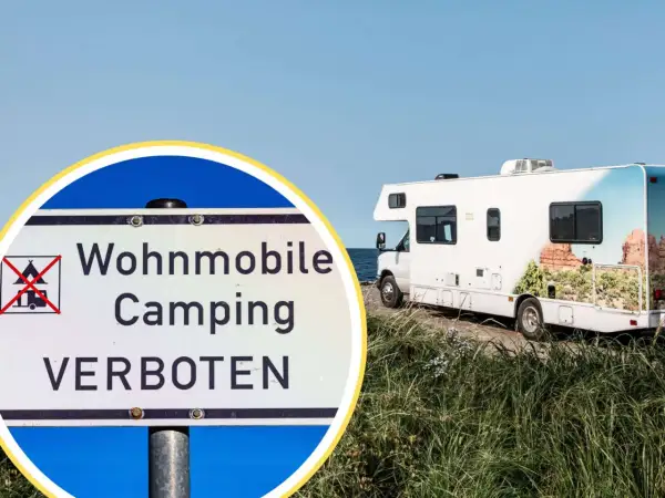 Schild: Wohnmobile Camping VERBOTEN. Ein Wohnmobil steht am Meer, aber hier ist kein Platz für strafe wildcampen.