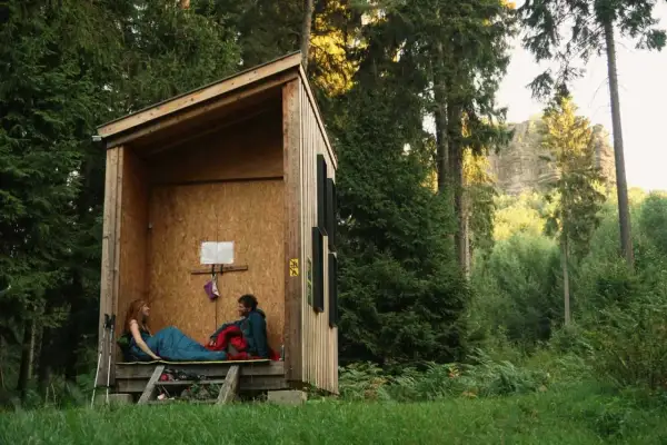 Ein Paar entspannt in einer Schutzhütte im Wald. Hier darf man im Wald schlafen und die Natur genießen.
