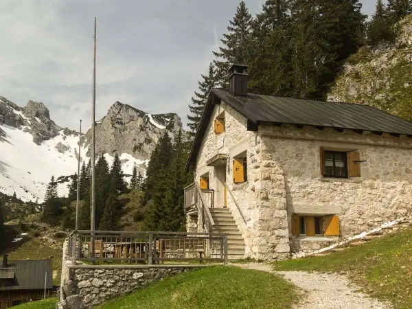 Steinernes Haus mit Holzterrasse und Bergkulisse im Tannheimer Tal. Ein Geheimtipp für Wanderer.