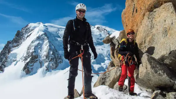 Zwei Bergsteiger auf dem Weg zur Mont Blanc Besteigung, umgeben von Schnee und Felsen.