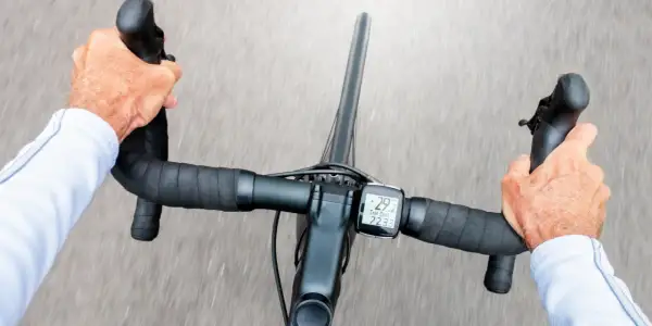 Hände greifen den Rennradlenker, während der Radcomputer 29,2 km/h anzeigt.