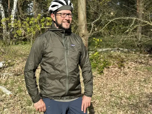 Mann mit Fahrradhelm und Patagonia Regenjacke im Wald. Die Jacke ist leicht und ideal für Outdoor-Abenteuer.