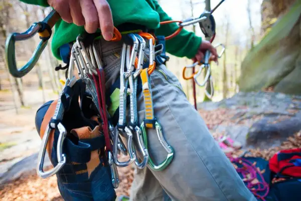 Kletterer mit Ausrüstung für trad klettern, Kletterschuhe hängen am Gurt.