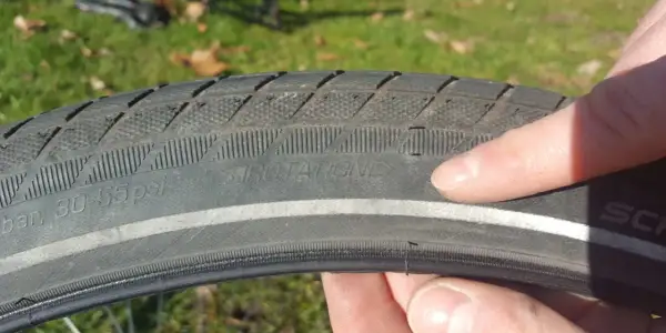 Finger zeigt auf abgefahrenen Fahrradreifen mit der Aufschrift "ROTATION". Zeit, wann Fahrradreifen wechseln.